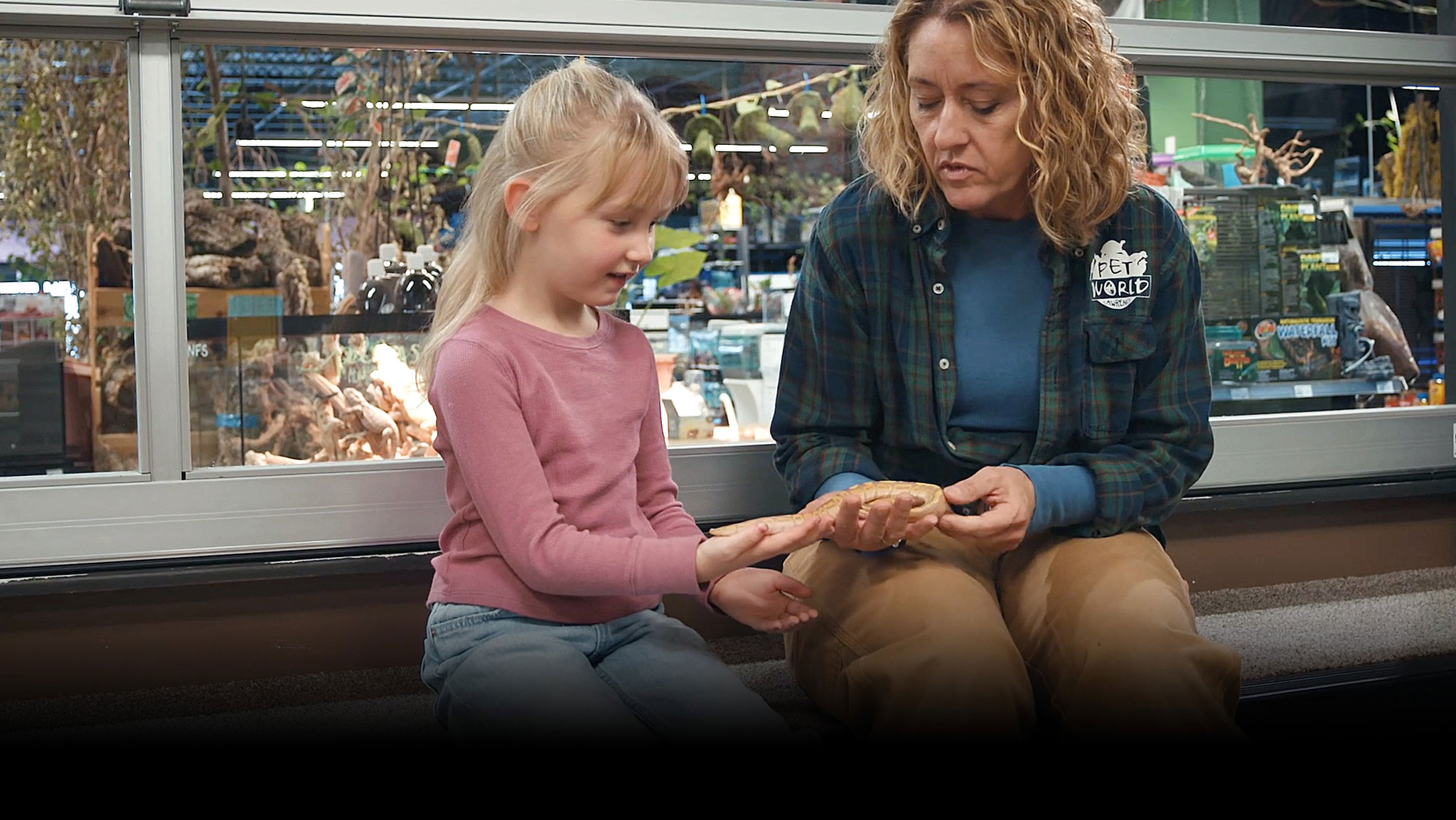 pet world employee showing a young girl a snake